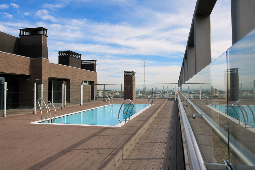 110 Dwellings Paseo de la Castellana 3 Piscina de diseño en azotea de edificio, con cubierta de madera y vistas a Madrid.