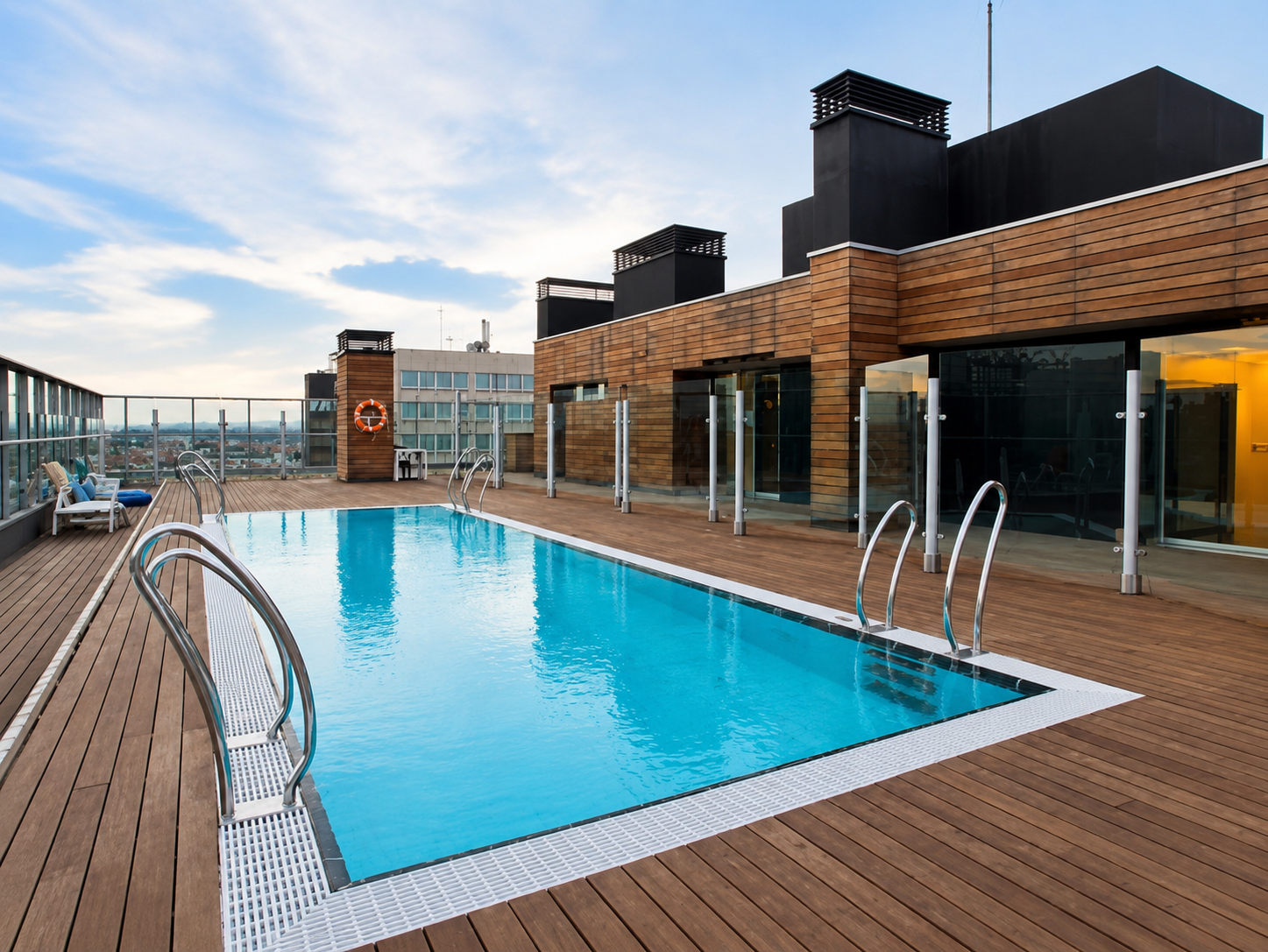 Piscina de diseño en azotea de hotel, con tumbonas y vistas urbanas de Madrid.