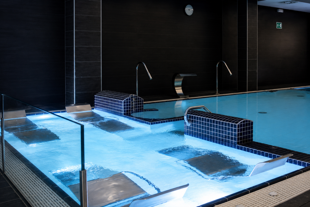 Piscina interior con asientos de hidromasaje y cascadas, ideal para renovación de piscinas en Guipúzcoa.