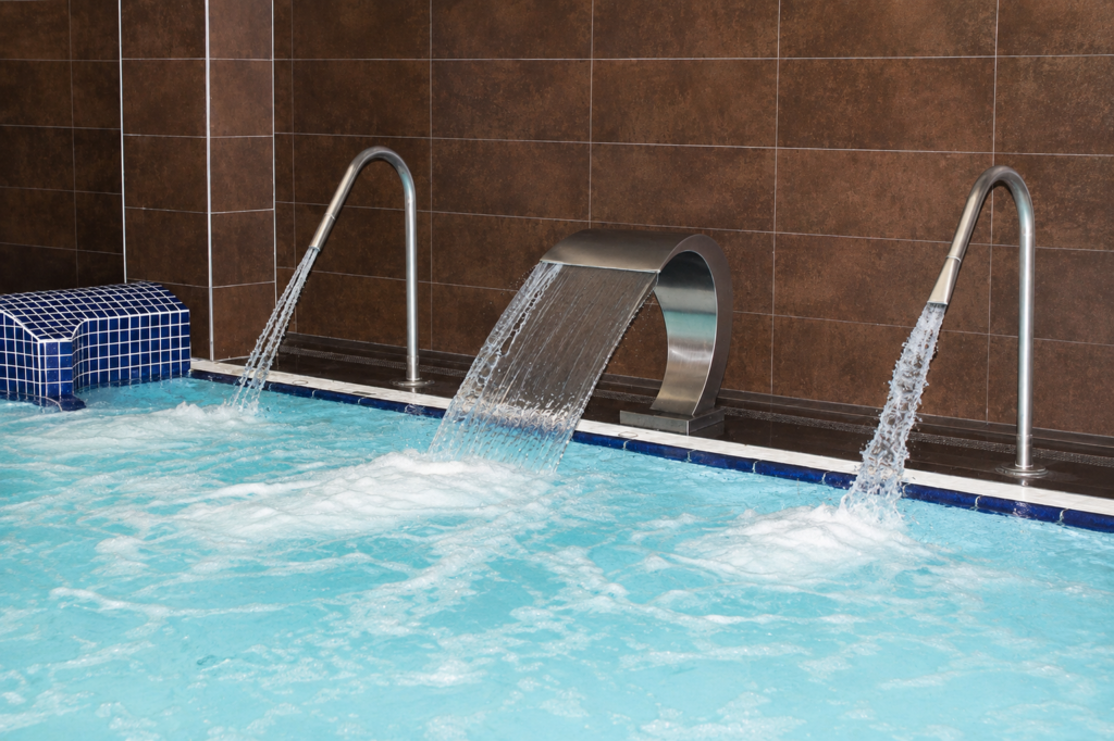 Piscina interior con cascada y chorros de agua, ideal para spas y centros deportivos.