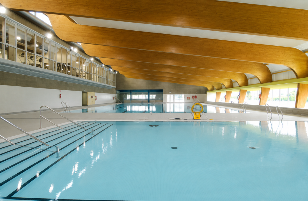 Piscina interior Myrtha de acero inoxidable laminado en el Centro Deportivo Mandor, con cubierta de madera y zona de entrenamiento.