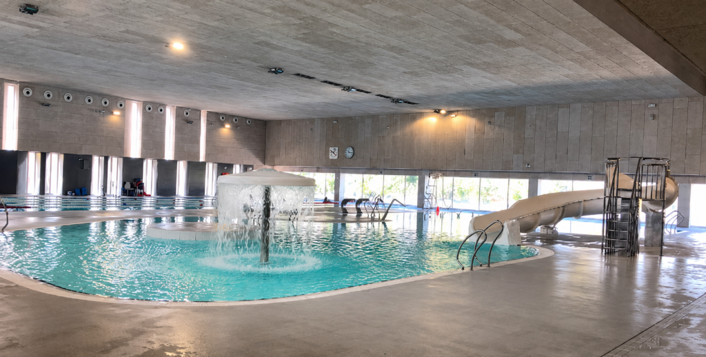 Piscina interior recreativa con tobogán y fuente, parte de la renovación de piscinas municipales.