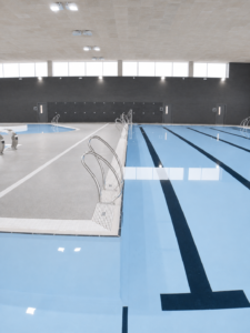 Piscina interior de competición, carriles de natación y escaleras metálicas.