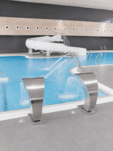 Piscina interior recreativa con tobogán y cascadas, parte de la construcción de piscinas municipales.