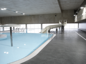 Piscina interior recreativa con tobogán, parte de la construcción de piscinas municipales.
