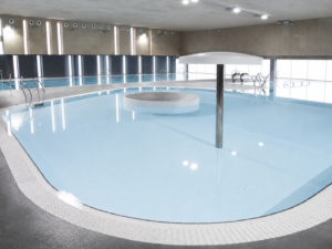 Piscina interior moderna con isla central, ideal para centros cívicos.