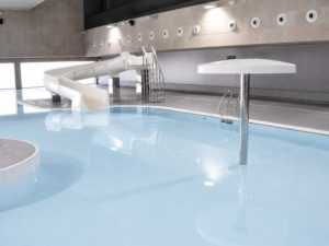 Piscina interior recreativa con tobogán y cubierta Myrtha Pools, parte de la construcción de piscinas municipales.