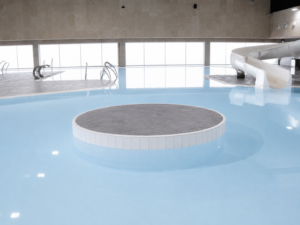 Piscina cubierta recreativa con tobogán y plataforma central