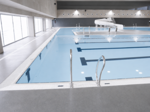 Piscina interior moderna con carriles de natación y toboganes, parte de la construcción de piscinas municipales.