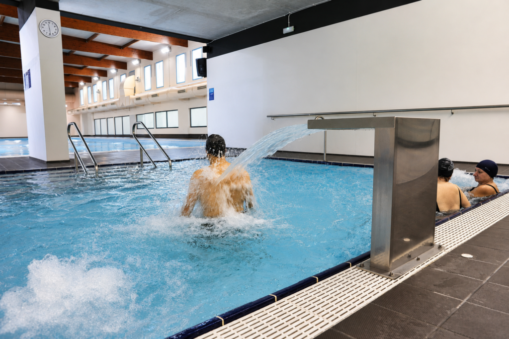 Piscina interior recreativa con cascada y personas disfrutando en Vilanova.
