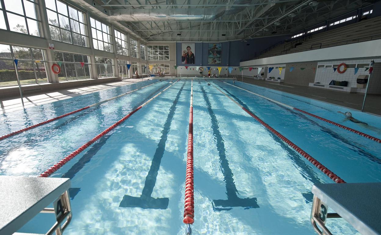 Piscina cubierta de competición con carriles de natación y gradas, lista para renovación.