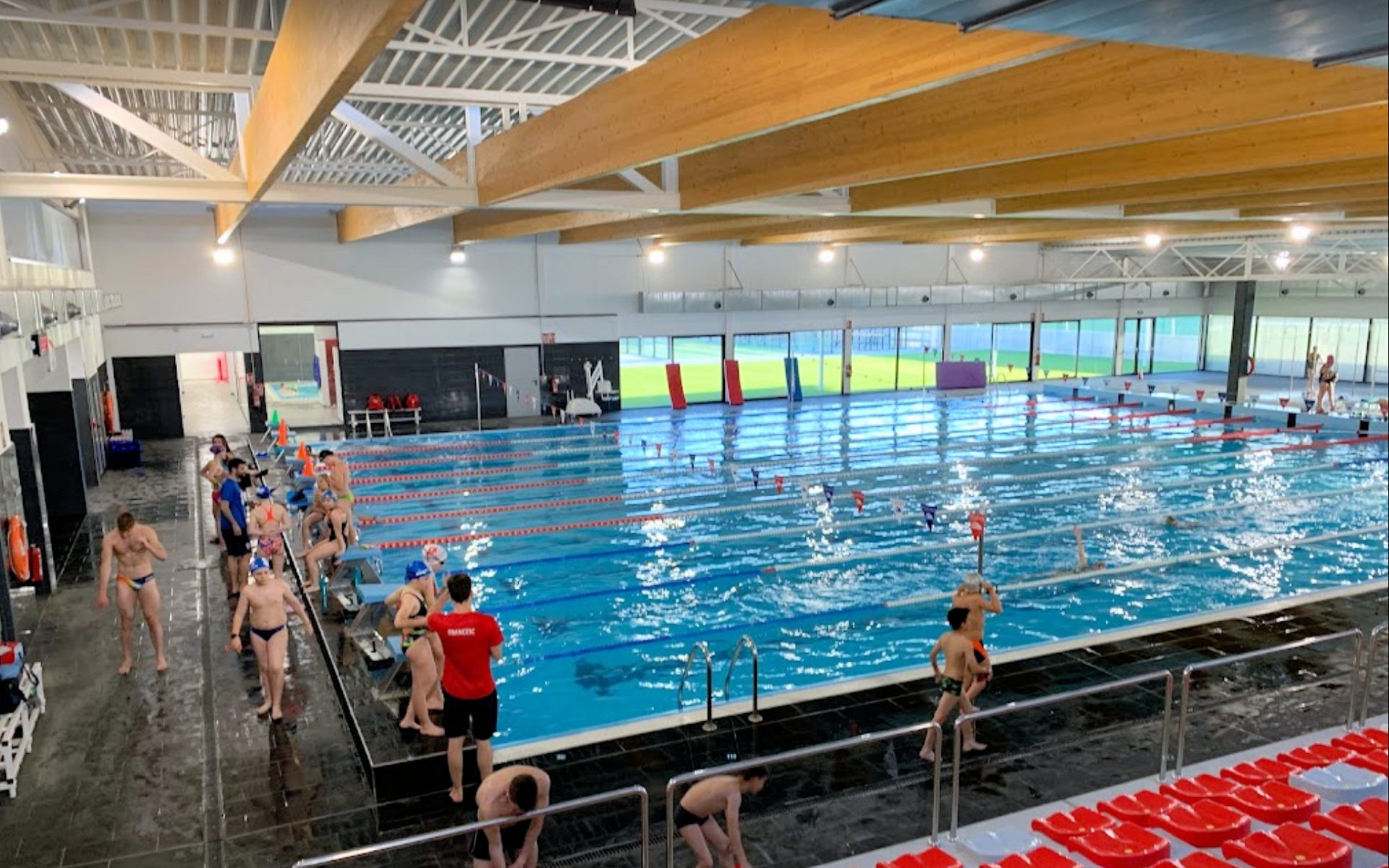 Piscina interior de competición Esportiu Tortosa con carriles de natación y nadadores.