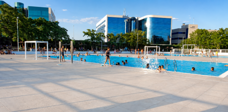 Piscinas descubiertas de Palomeras con bañistas bajo edificios modernos