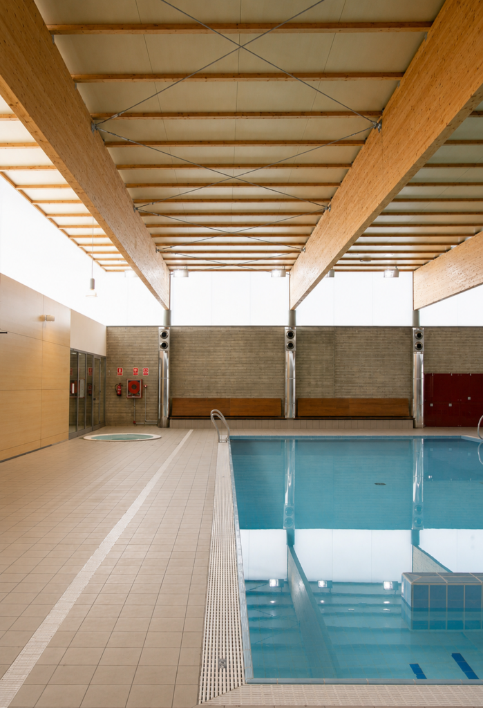 Piscina Myrtha interior con estructura de madera y zona wellness.