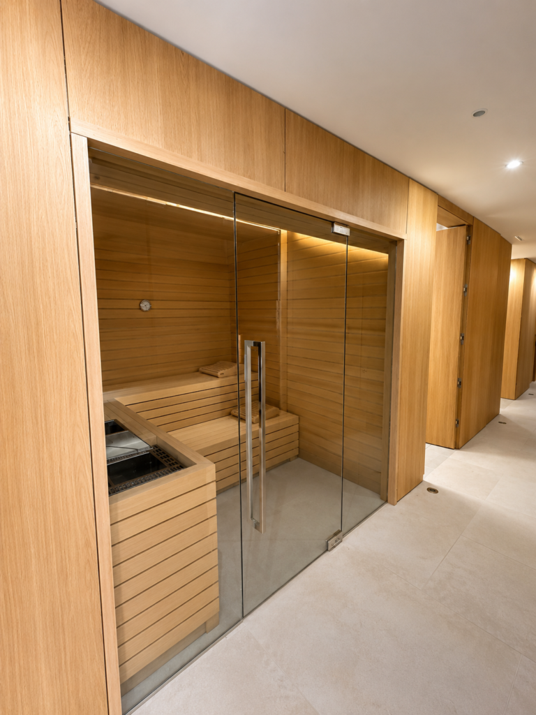 Sauna de madera en Village Verde fase II, con puerta de cristal y moderno diseño.