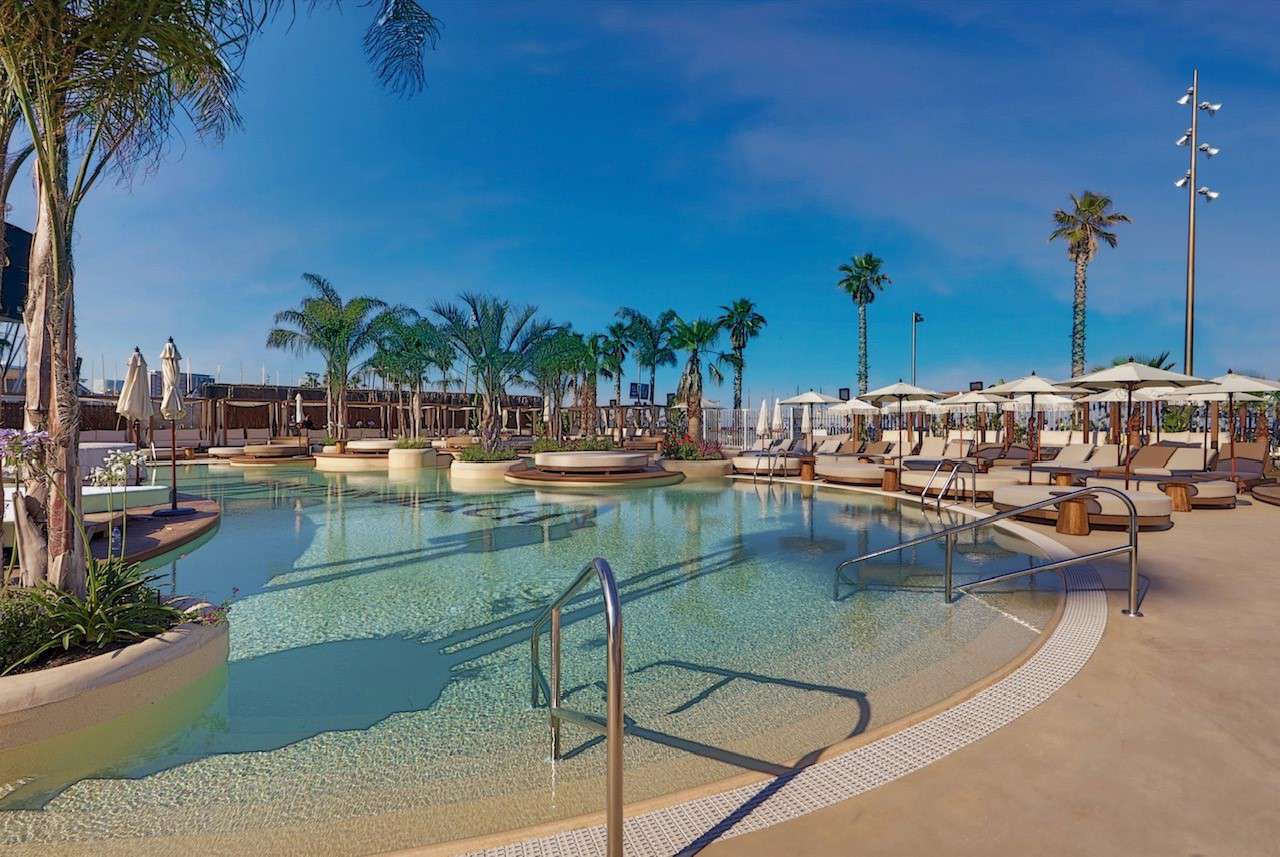 Bastian Beach Club 1 Bastian Beach Club: piscina exterior de diseño con tumbonas y palmeras.