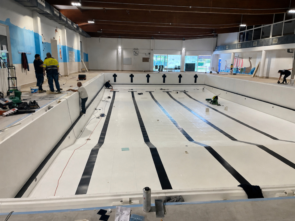 Piscina cubierta Myrtha Pools en Etxebarri, Molins de Rei, con carriles de natación y operarios trabajando.