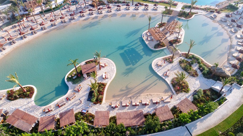 Piscinas de arena 1 Gran laguna artificial con fondo de arena y tumbonas en resort
