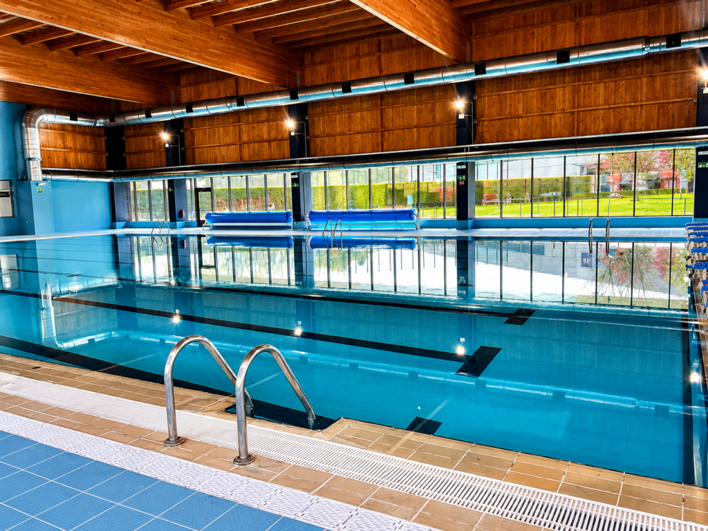 Piscina interior de competición de Alpe Pools, con carriles de natación y estructura de madera.