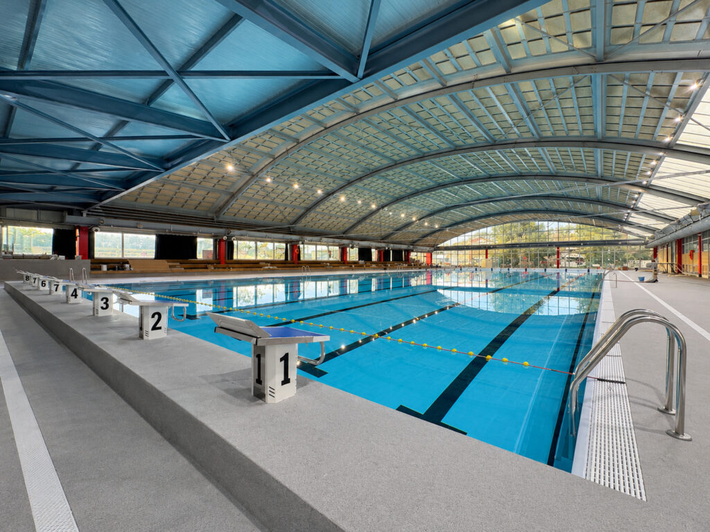 Piscina cubierta de competición en Molins de Rei con carriles y estructura metálica.